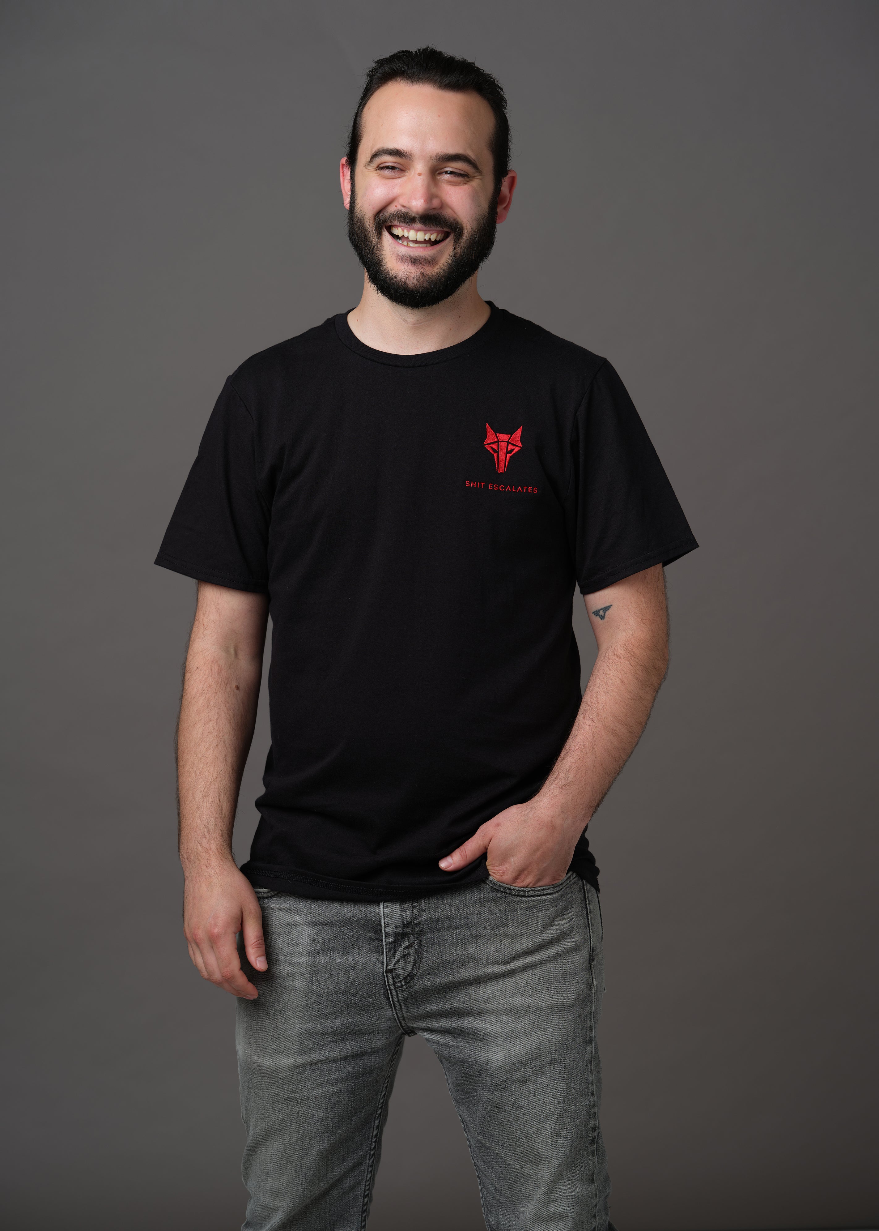 Black shirt with red Howler wolf sigil and 'Shit Escalates' embroidered below on left chest