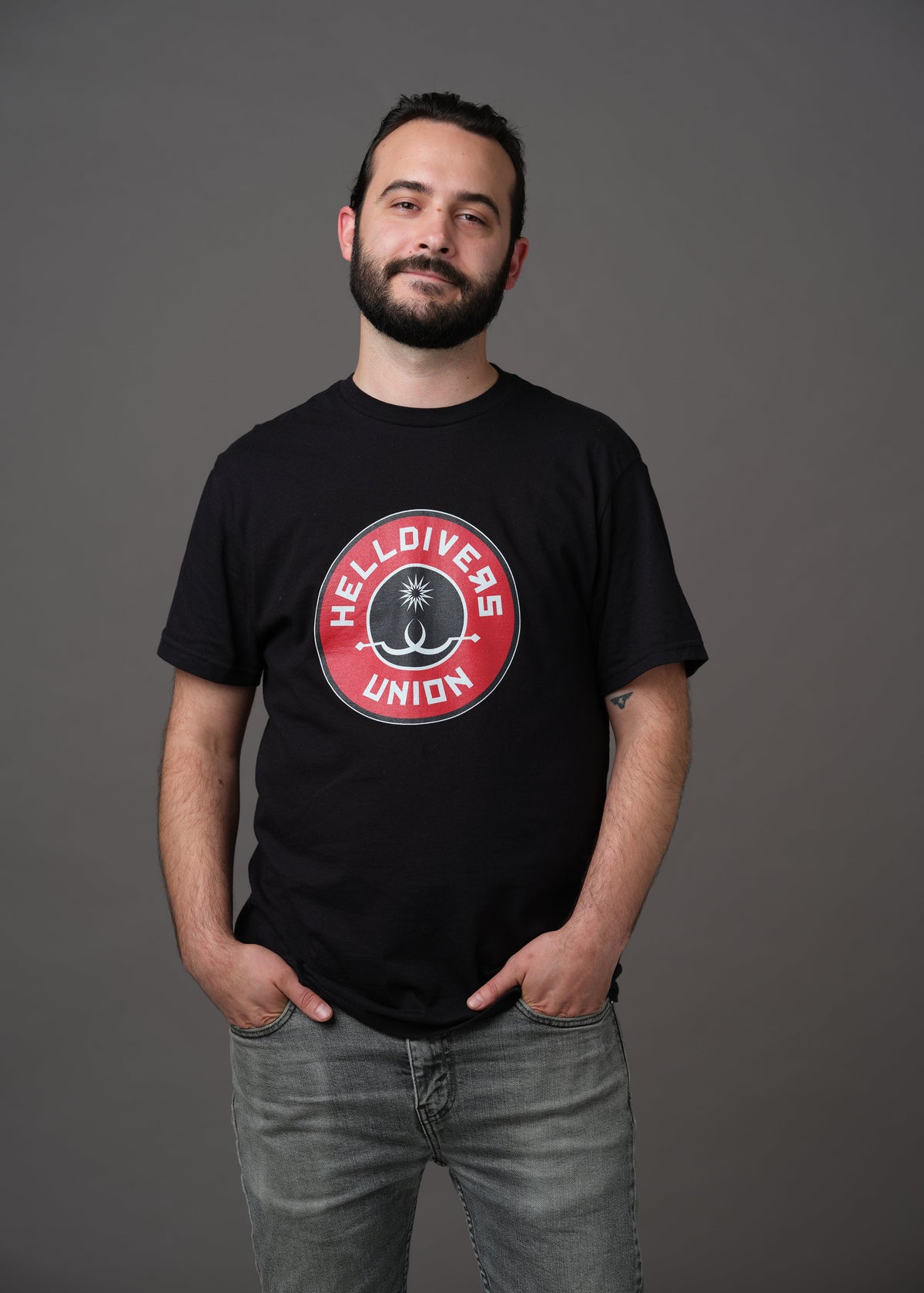 Black shirt with round black white and red design with two white sling blades and a white star surrounded by the words Helldivers Union