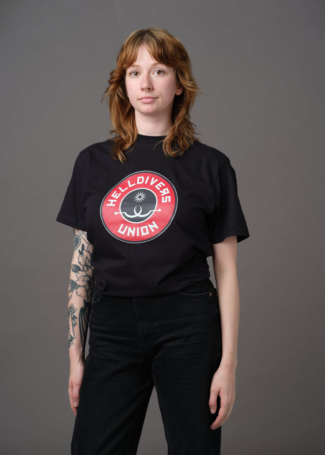 Black shirt with round black white and red design with two white sling blades and a white star surrounded by the words Helldivers Union