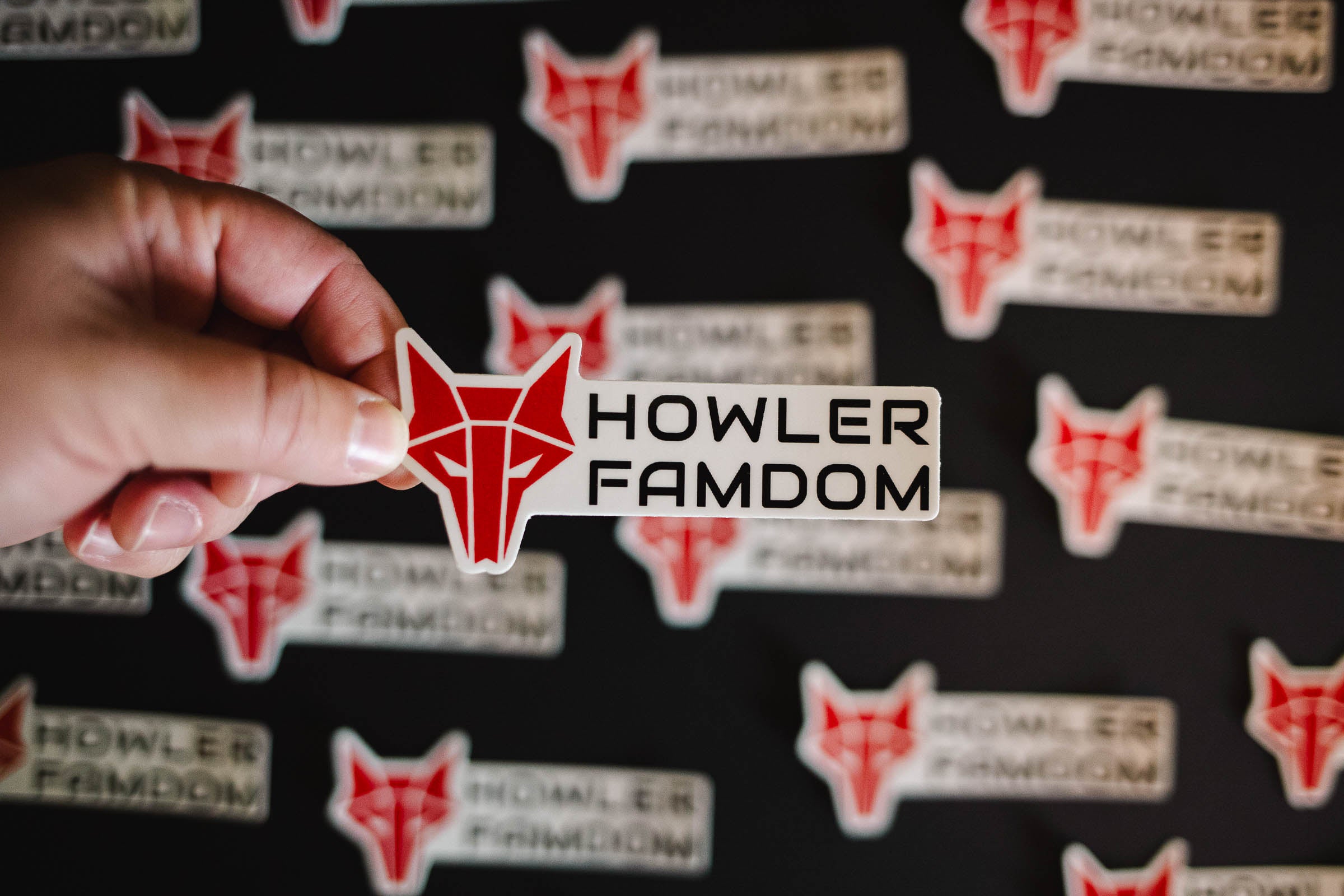 White sticker with red wolf Howler sigil and the words Howler Famdom in black