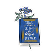 Load image into Gallery viewer, Sticker with blue flowers inside a hardcover blue book with &quot;there is defiance in being a dreamer&quot; and a constellation with seven stars 
