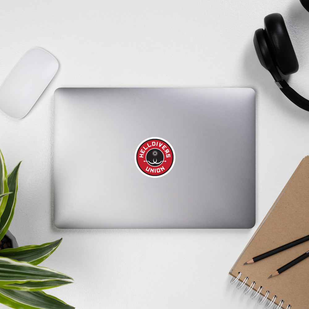 Round sticker with black white and red design with two white sling blades and a white star surrounded by the words Helldivers Union