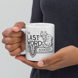 White mug that says The Last Word Bookshop and has a fluffy cat sitting next to books